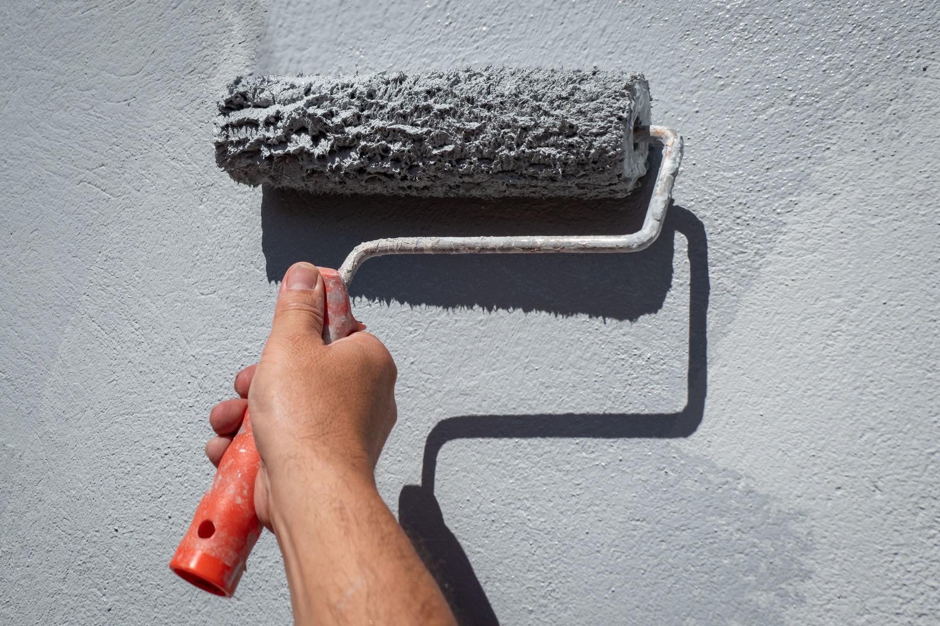 Painter with roller in hand painting the wall